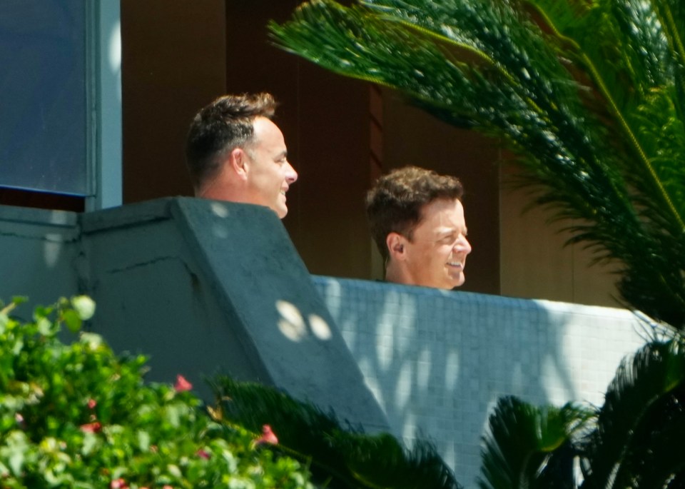 two men are sitting on a balcony talking to each other