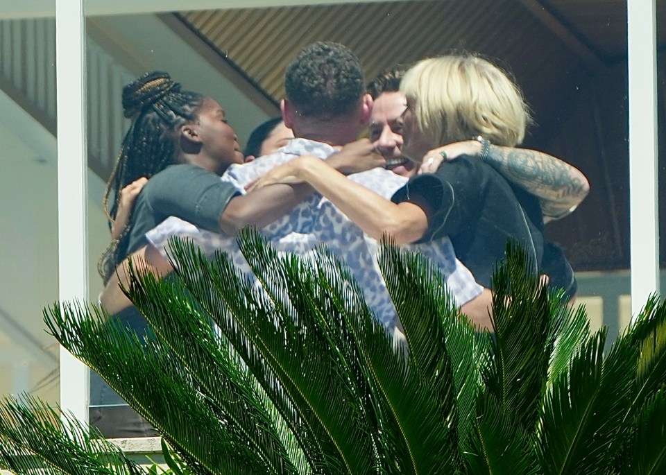 a group of people hugging each other in front of a window