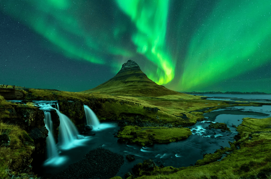 a waterfall in front of a mountain with the aurora borealis behind it