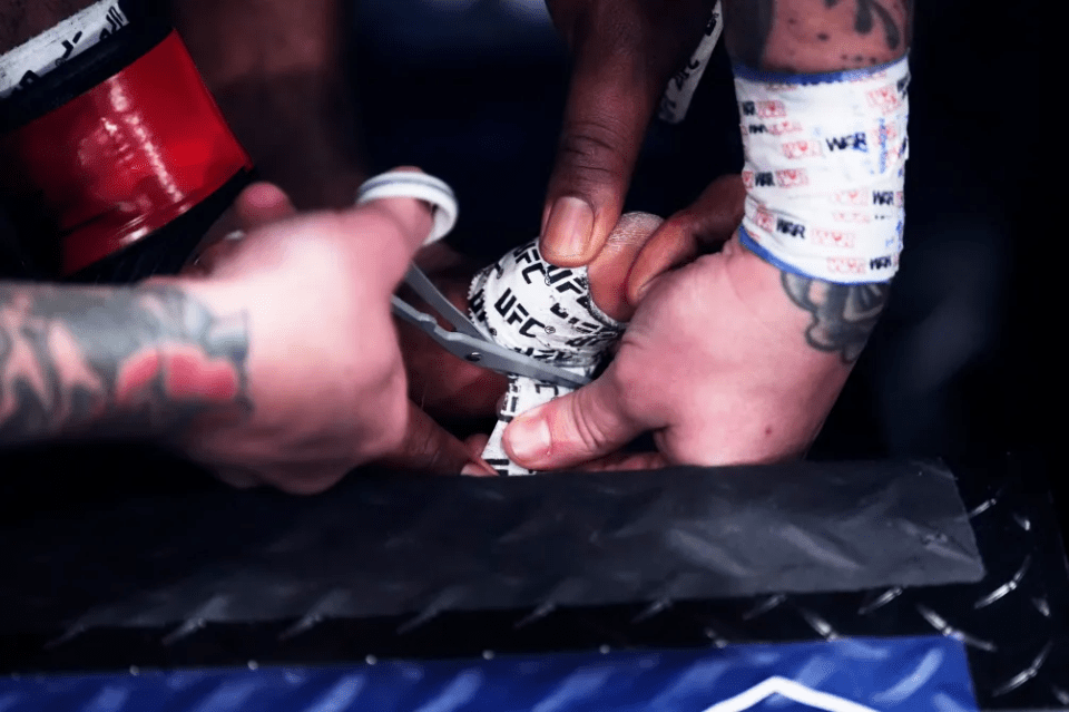 a person wrapping another person 's wrist with ufc tape