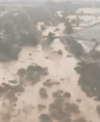 an aerial view of a flooded area with trees in the background