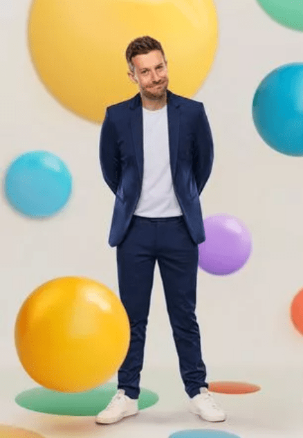 a man in a suit is standing in front of colorful balloons .