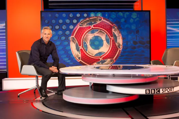 a man sits in front of a bbc sport table