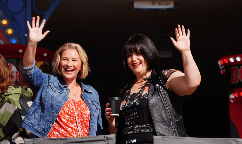 two women waving in front of a sign that says bo