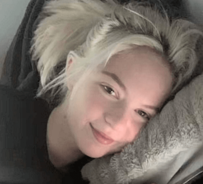 a woman with blonde hair is laying on a blanket and smiling .