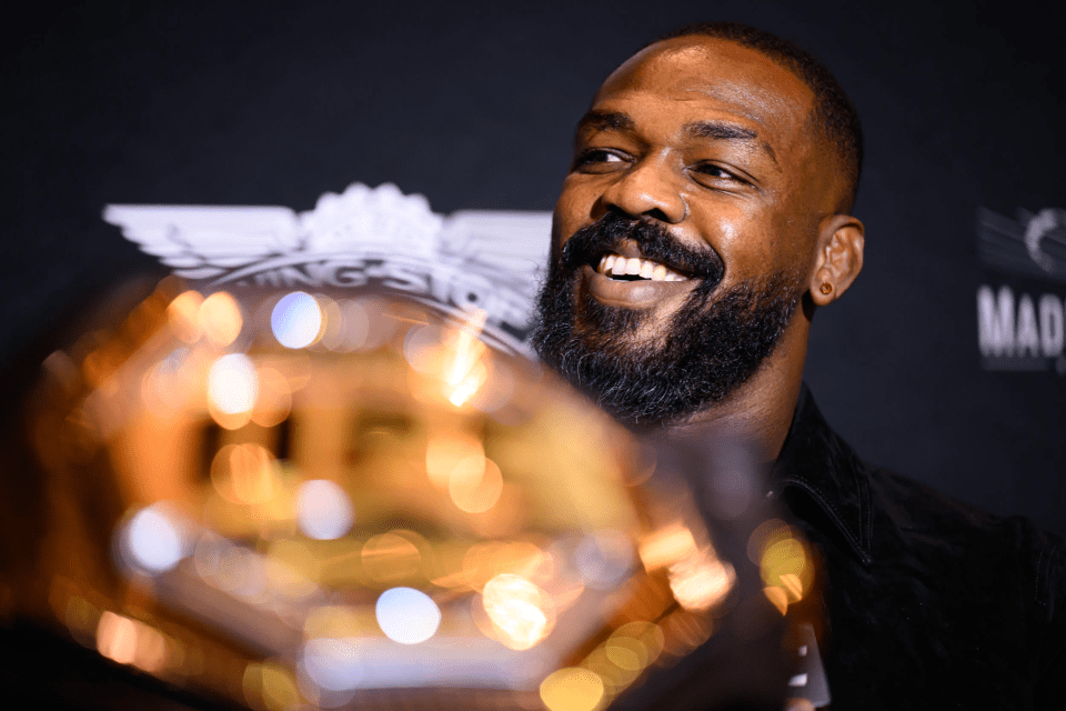 a man with a beard holds a trophy in front of a sign that says mad