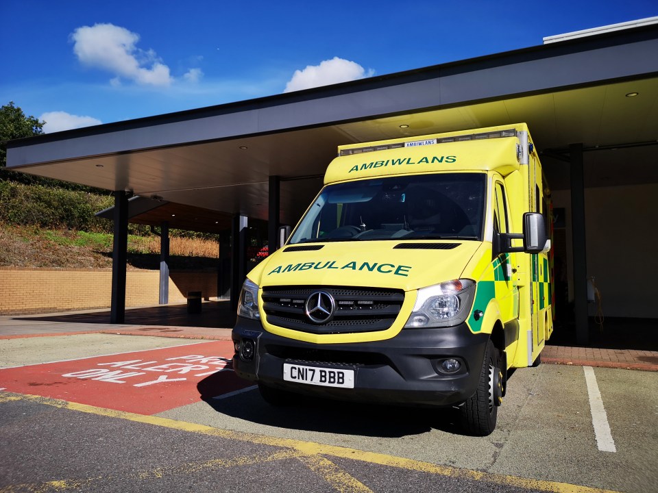 a yellow and green ambulance is parked in front of a building