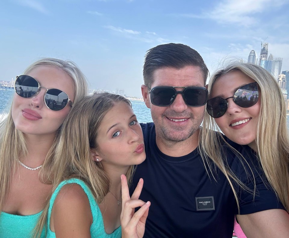 a man wearing a black dolce & gabbana shirt poses with two girls