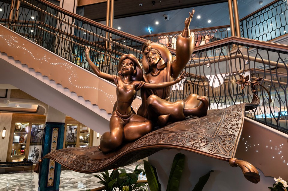 A bronze statue of Aladdin and Jasmine greets you in the Grand Halls of Disney Treasure, the latest cruise ship in a six-strong fleet