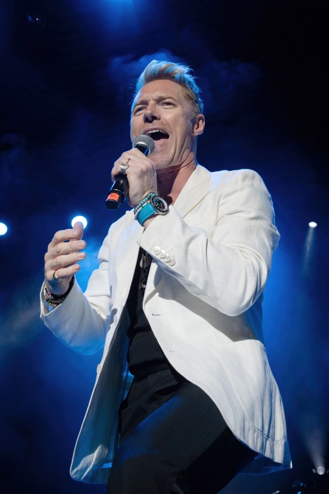 a man in a white jacket singing into a microphone