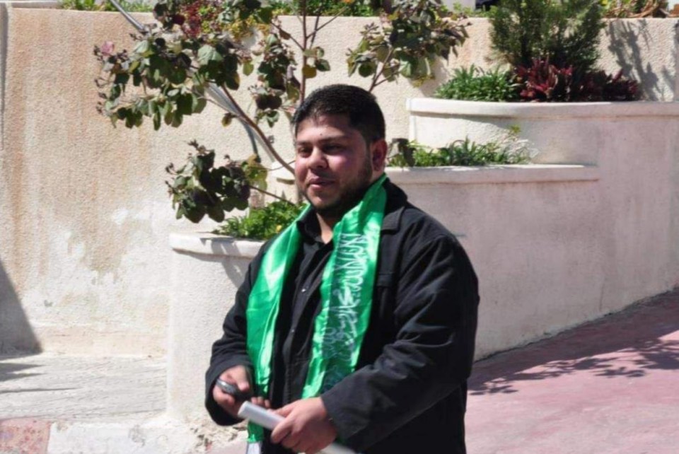 a man wearing a green scarf with arabic writing on it