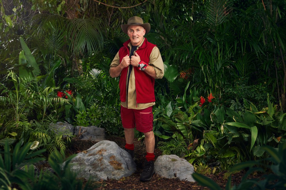 a man in a cowboy hat is standing in the jungle