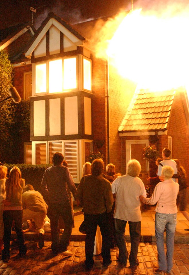 A house fire on a Coronation Street set with onlookers.