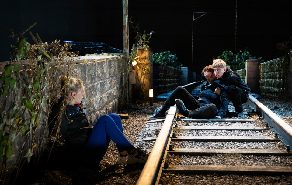 a group of people are sitting on train tracks at night