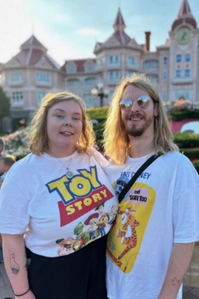 a man and a woman wearing toy story shirts pose for a picture