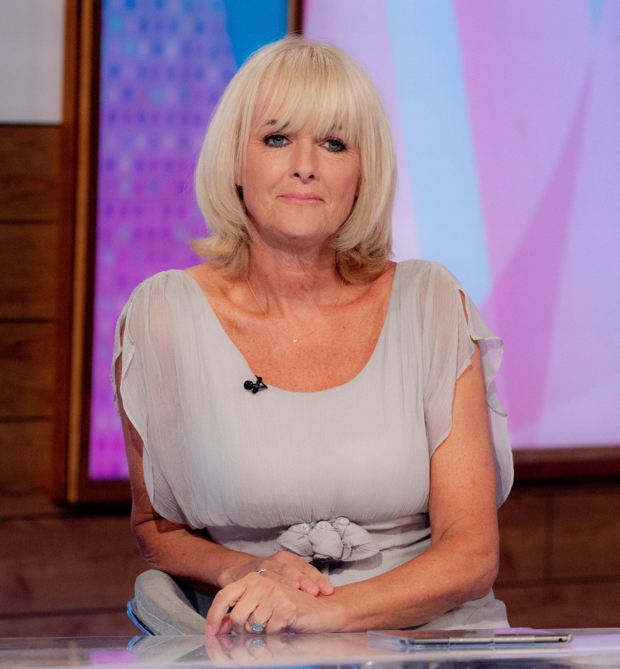 a woman sits at a table with her hands folded