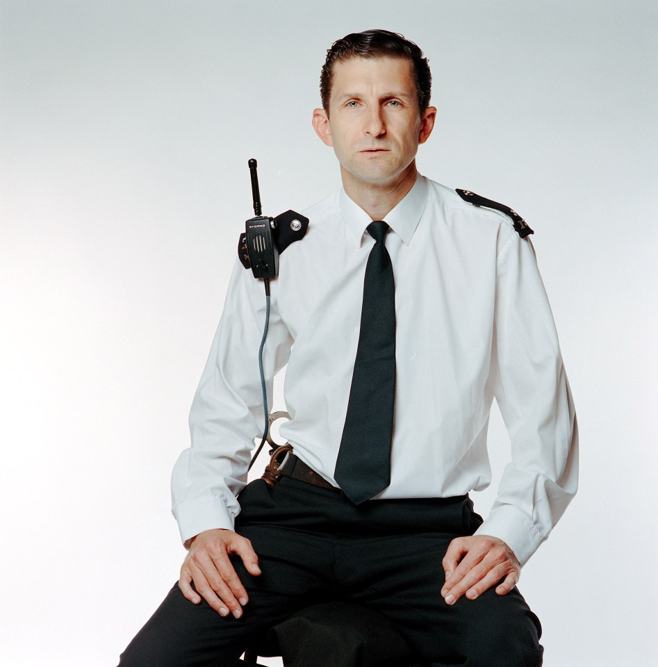 a man in a metropolitan police uniform looks at the camera