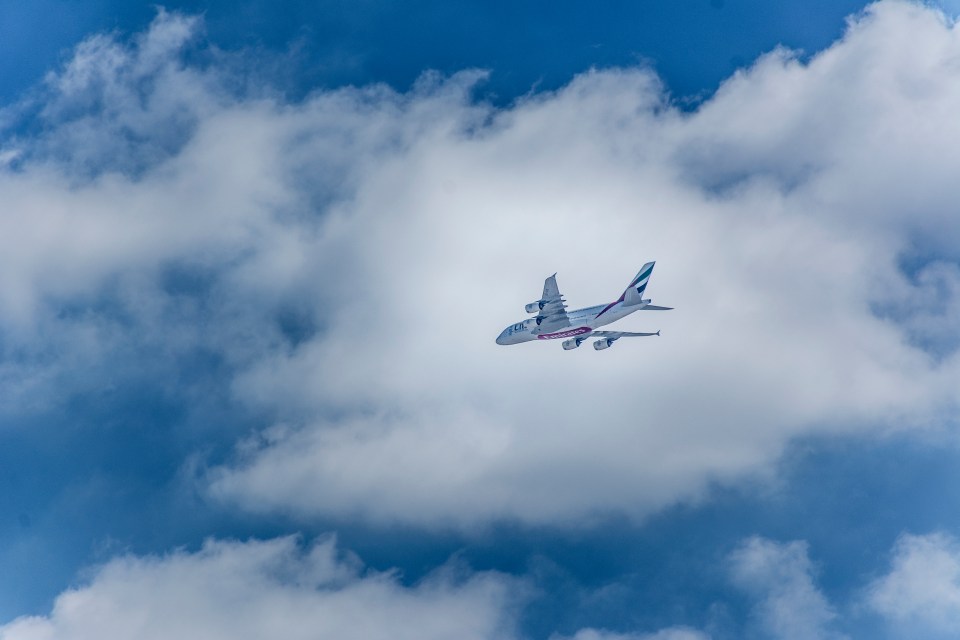 an emirates airplane flies through the clouds