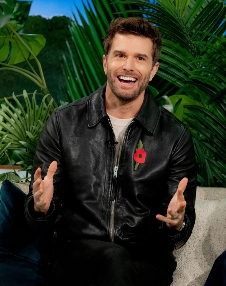 a man wearing a black leather jacket with a red poppy on it