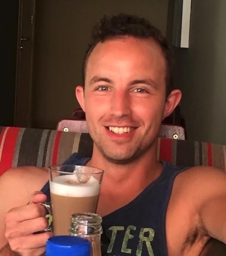 a man in a tank top with the word ter on it is holding a cup of coffee