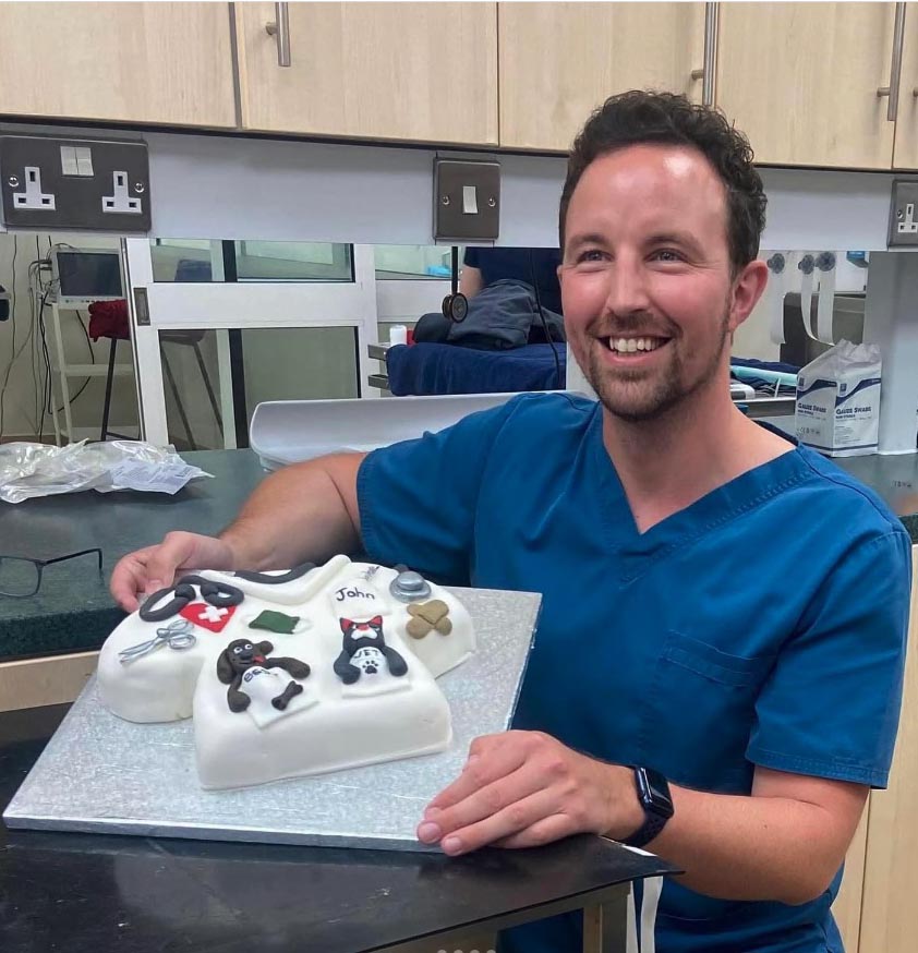 a man in scrubs is holding a cake that says john on it