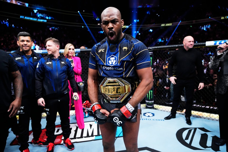 a man wearing a ufc championship belt stands in front of a crowd