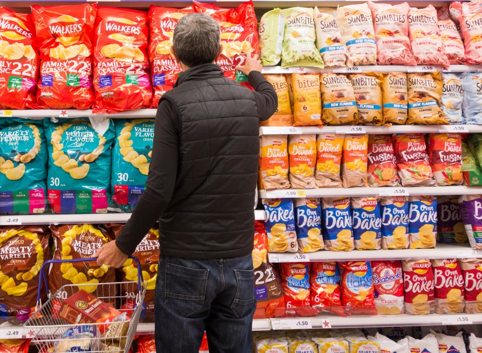 K0K3TM Man buying large mult-pack of crisps in Tesco supermarket. UK