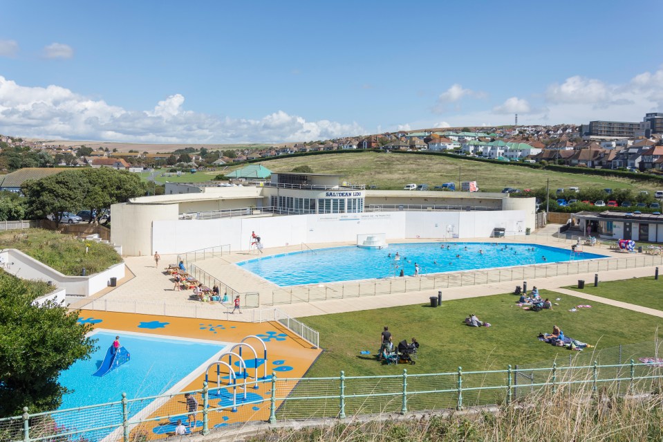 a large swimming pool is surrounded by a fence and people are swimming in it