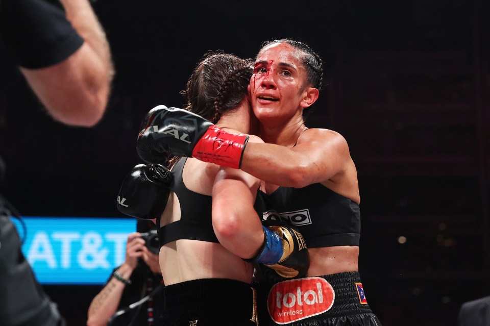 two female boxers hugging with one wearing a total sticker on her shorts