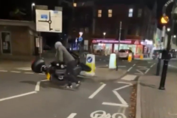 a person is doing a handstand on a motorcycle on the street .