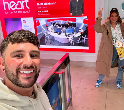 a man and woman standing in front of a sign that says heart