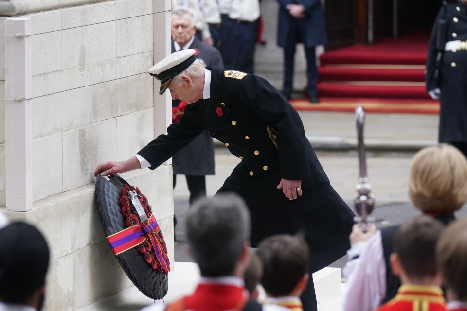 a man in a navy uniform is putting a wreath on a wall