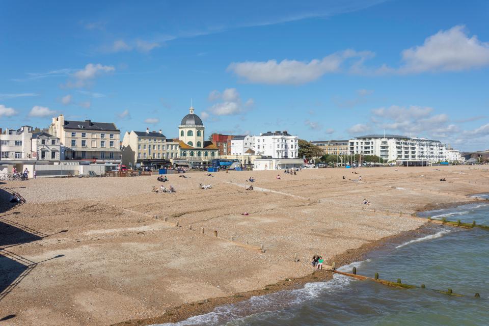 a large sandy beach with buildings in the background