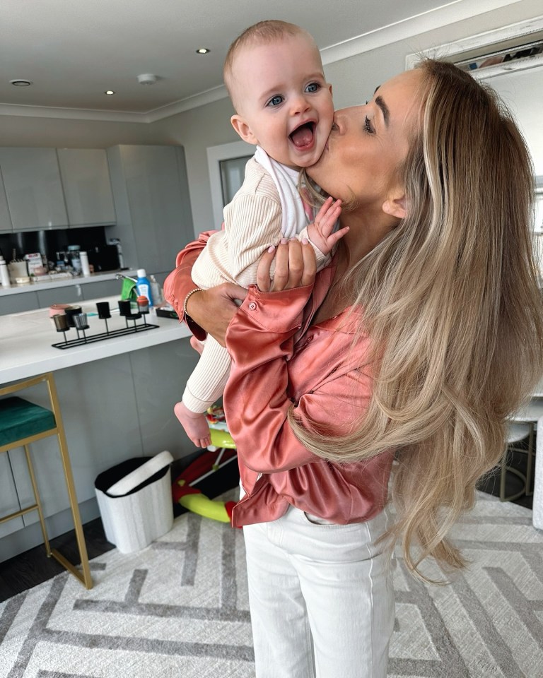 a woman holds a baby in her arms and kisses it on the cheek