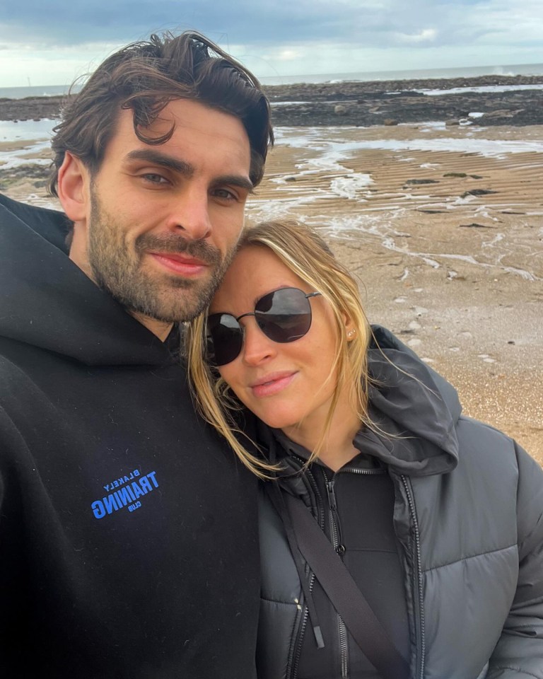 a man and a woman are posing for a picture on a beach