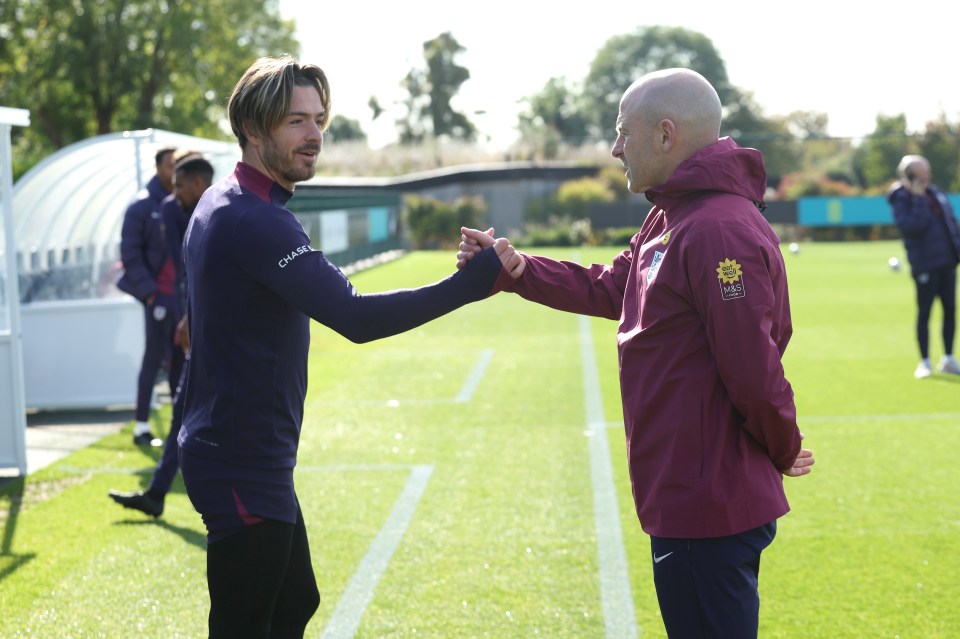 two men shaking hands on a soccer field with one wearing a jacket that says channel