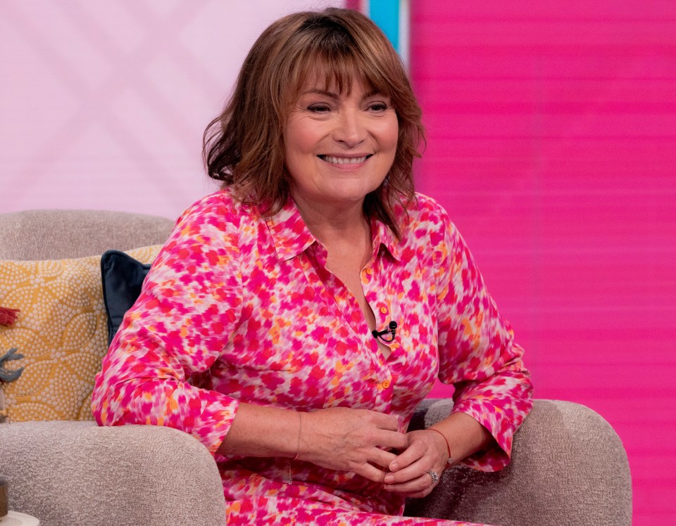 a woman in a pink floral shirt sits in a chair