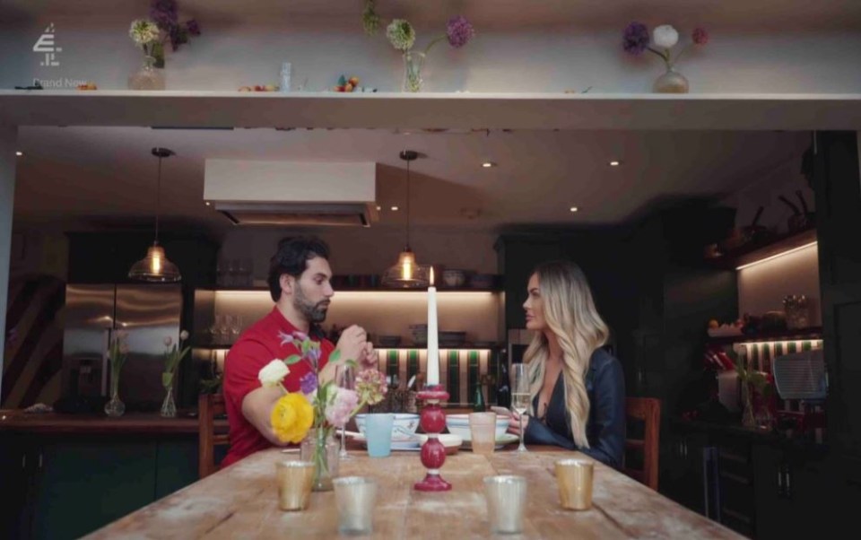 a man and a woman sit at a table with a bbc logo in the background