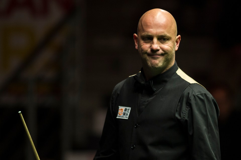 a man holding a pool cue and wearing a shirt that says snooker on it