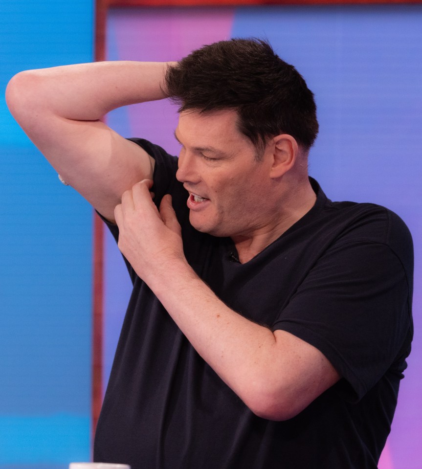 a man in a black shirt is scratching his armpit