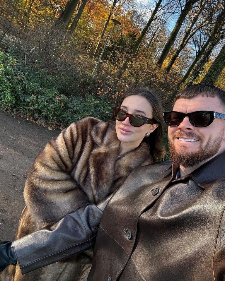 a man and a woman wearing fur coats and sunglasses pose for a picture