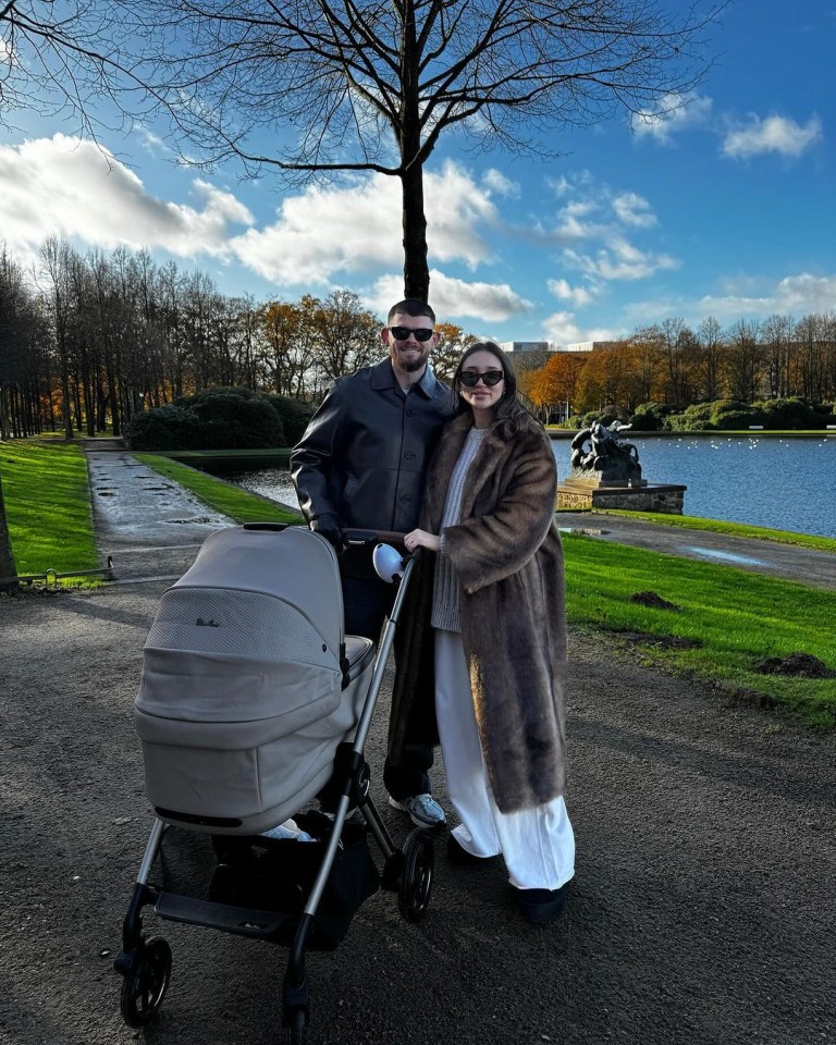 a man and woman standing next to a baby in a stroller