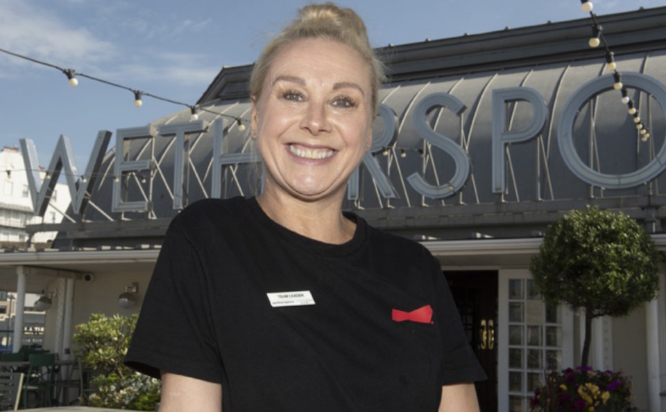 a woman stands in front of a sign that says " wetherspoon "