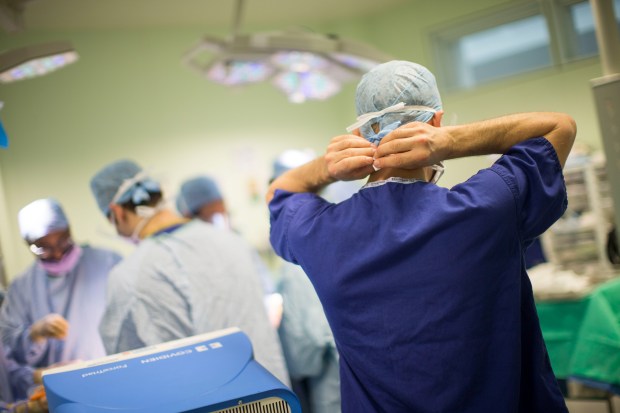 a surgeon adjusts his surgical gown in an operating room