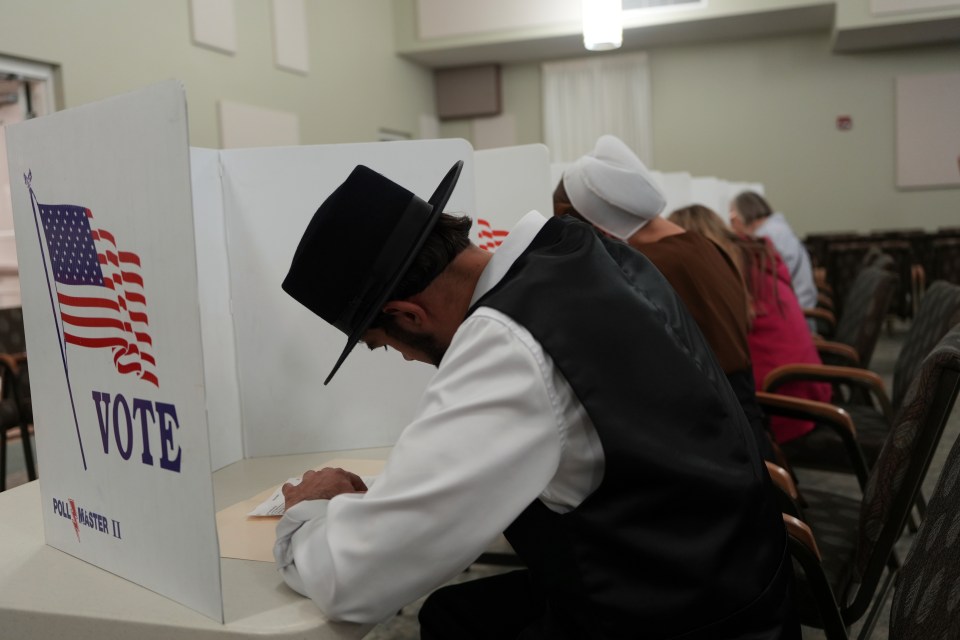 a man sits in front of a voting booth that says vote