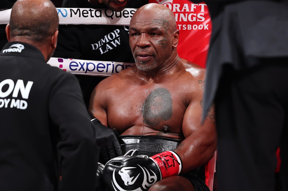 mike tyson talks to a referee while wearing boxing gloves