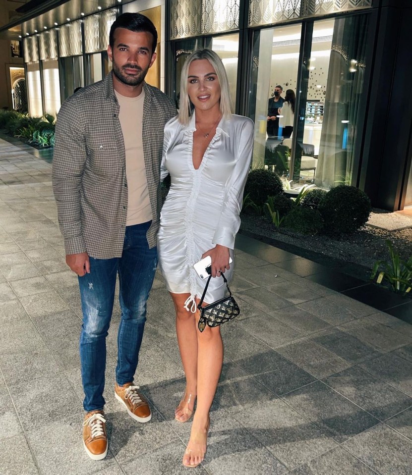 a man and a woman pose for a picture on a sidewalk