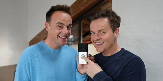 two men are smiling and holding a ring doorbell