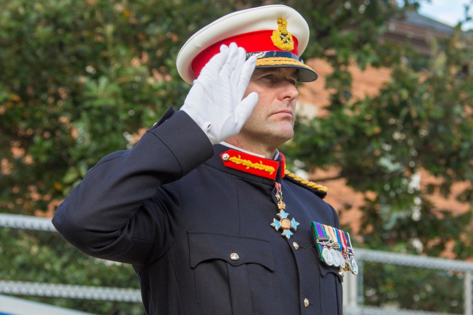 a man in a military uniform salutes in front of a building