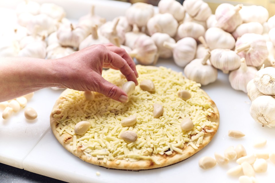 a person is putting garlic on top of a pizza